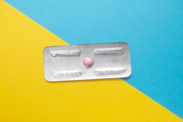 Blister di pillole su sfondo bicolore azzurro e giallo