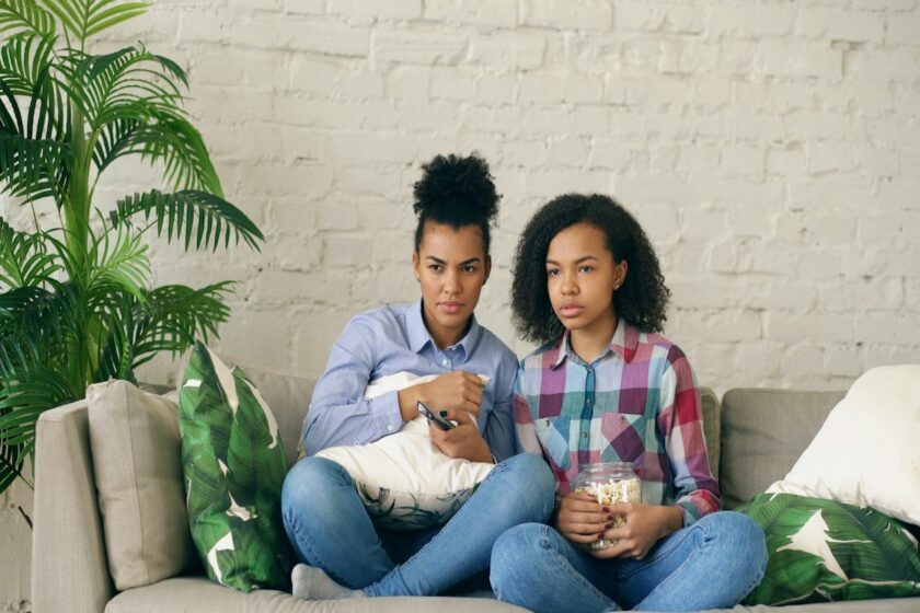 Gruppo di donne sul divano che guardano una serie tv con popcorn e sorrisi