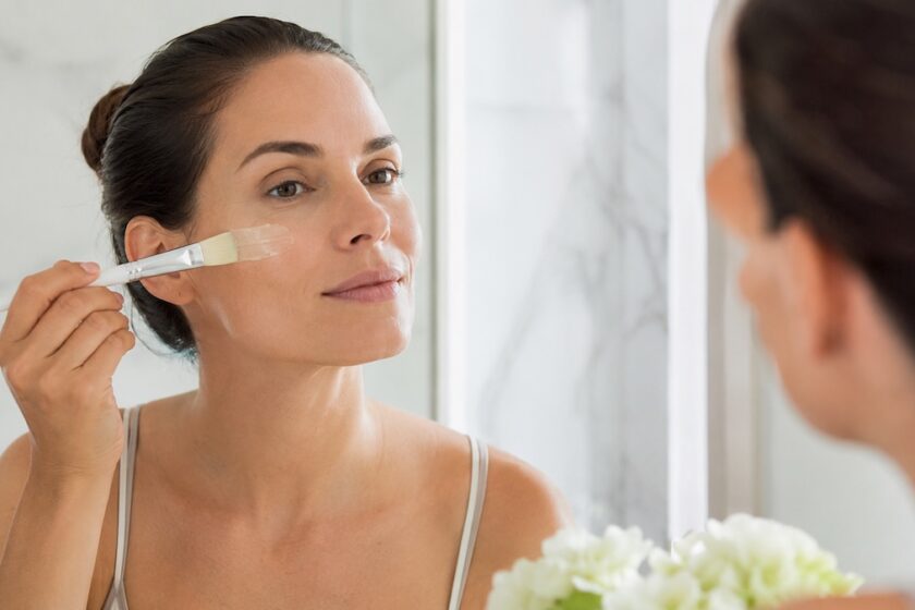 Donna che applica un peeling casalingo delicato sul viso con un pennello cosmetico